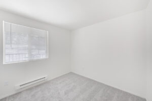 Interior Unit Bedroom, White walls, neutral toned carpeting, double window.