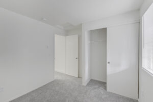 Interior Unit Bedroom, Sliding closet doors, white walls, neutral toned carpeting.