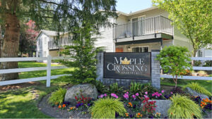 Exterior Maple Crossing Front Signage, meticulous landscaping, lush foliage, photo taken on a sunny day.